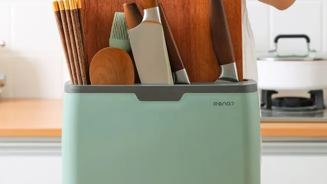 Kitchen utensils and knives in a green container