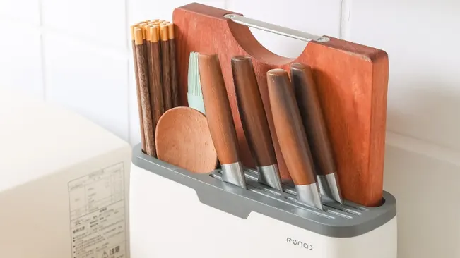 Wooden kitchen tools and knives stored in a white container with slots