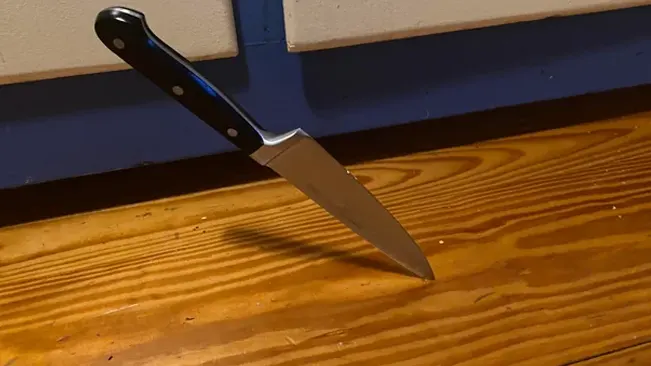 chef's knife standing blade down on a wooden floor