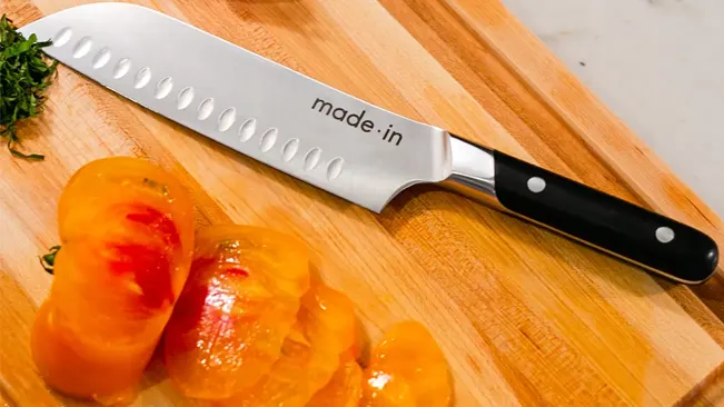 Santoku knife with sliced tomatoes on a wooden cutting board, showcasing safety and precision